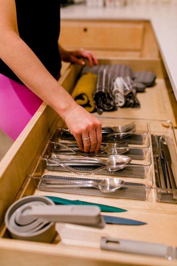 Hand placing utensils into a kitchen drawer with clear dividers