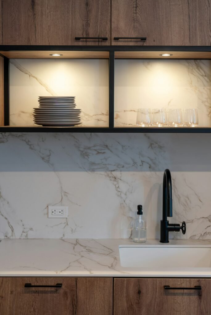 Small kitchen sink with open shelves and stacked plates above